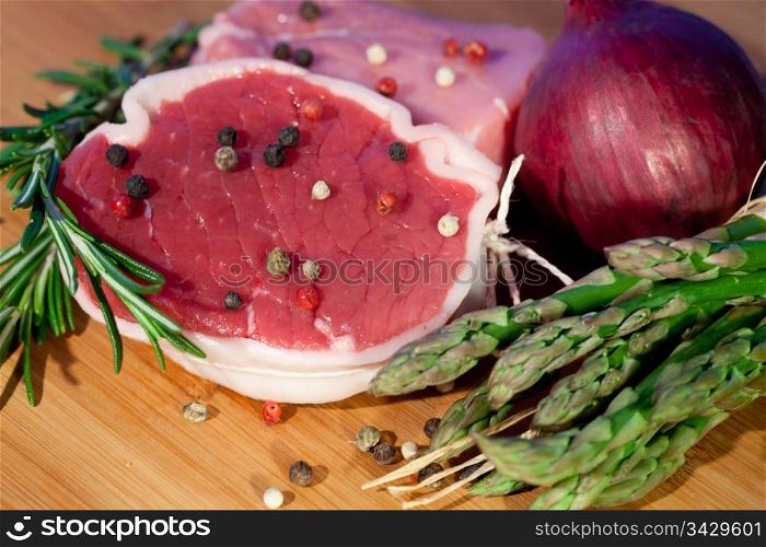 Raw piece of beef with rosemary and asparagus