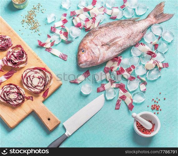 Raw pink dorado fish cooking preparation with ingredients and knife on light blue kitchen table background, top view, flat lay. Seafood concept