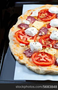 Raw pizza dough with mozzarella and proscuitto on top