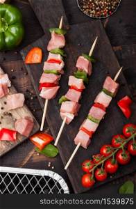 Raw pork and chicken kebab with paprika on chopping board with fresh vegetables and disposable charcoal grill on wooden background. Salt and pepper with lettuce and paprika pepper.