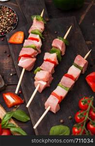 Raw pork and chicken kebab with paprika on chopping board with salt and pepper on wood.