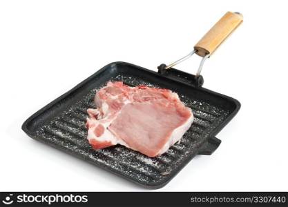 raw pork chop on a griddle with salt isolated on white