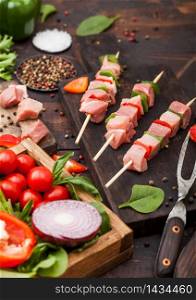 Raw pork kebab with paprika on chopping board with fresh vegetables on wooden background with fork. Salt and pepper with lettuce and paprika and cherry tomatoes.