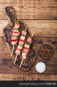Raw pork kebab with paprika on vintage chopping board with salt and pepper on wood.