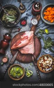 Raw Pork knuckle eisbein , cooking preparation for roast with gut vegetables in bowls with rustic meat knife and fork on cutting board, top view. Country style