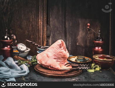 Raw pork knuckle eisbein, preparation on rustic kitchen table at wooden background, front view, place for text