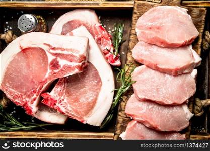 Raw pork meat with herbs and spices in a tray. On rustic background.. Raw pork meat with herbs and spices in a tray.
