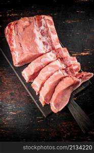 Raw pork on a cutting board. Against a dark background. High quality photo. Raw pork on a cutting board.