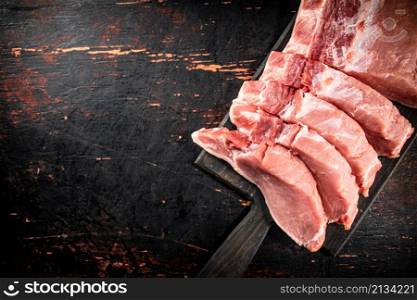 Raw pork on a cutting board. Against a dark background. High quality photo. Raw pork on a cutting board.