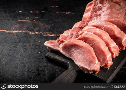 Raw pork on a cutting board. Against a dark background. High quality photo. Raw pork on a cutting board.