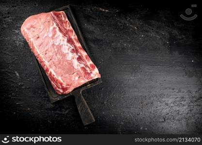 Raw pork on a cutting board. On a black background. High quality photo. Raw pork on a cutting board.