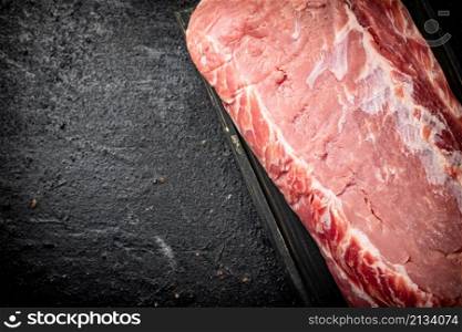 Raw pork on a cutting board. On a black background. High quality photo. Raw pork on a cutting board.