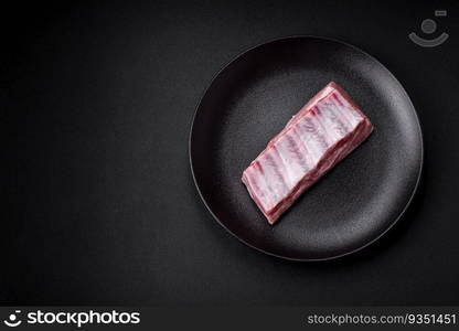 Raw pork ribs with salt, spices and herbs on textured concrete background. Raw pork ribs with meat with salt, spices and herbs