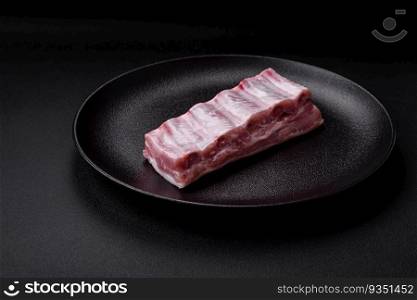 Raw pork ribs with salt, spices and herbs on textured concrete background. Raw pork ribs with meat with salt, spices and herbs