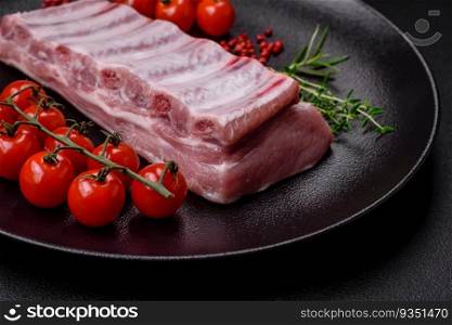 Raw pork ribs with salt, spices and herbs on textured concrete background. Raw pork ribs with meat with salt, spices and herbs