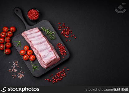 Raw pork ribs with salt, spices and herbs on textured concrete background. Raw pork ribs with meat with salt, spices and herbs