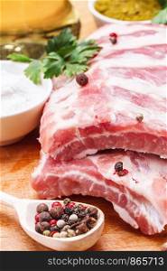 Raw pork ribs with spices and parsley on a wooden background