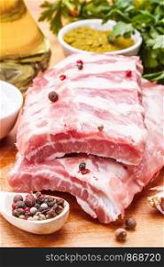 Raw pork ribs with spices and parsley on a wooden background