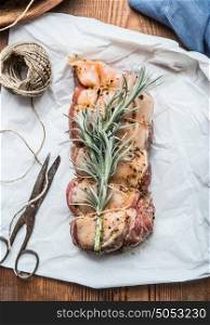 Raw Pork roast on white backing paper with rope and shears, cooking preparation, top view, close up