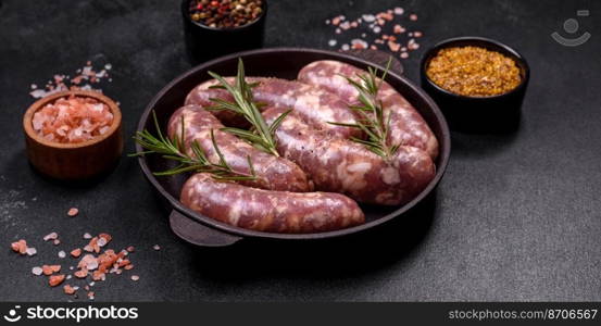 Raw pork sausages grill with spices and herbs on a dark concrete table. Cooking at home. Raw pork sausages grill with spices and herbs on a dark concrete table