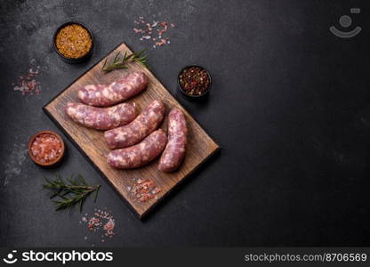 Raw pork sausages grill with spices and herbs on a dark concrete table. Cooking at home. Raw pork sausages grill with spices and herbs on a dark concrete table