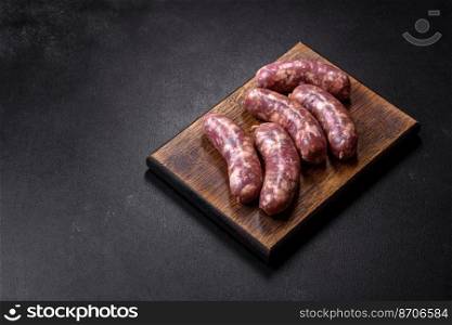 Raw pork sausages grill with spices and herbs on a dark concrete table. Cooking at home. Raw pork sausages grill with spices and herbs on a dark concrete table
