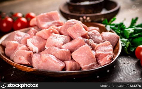 Raw pork sliced on a plate with tomatoes. On a wooden background. High quality photo. Raw pork sliced on a plate with tomatoes.