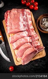 Raw pork sliced on a wooden cutting board. On a black background. High quality photo. Raw pork sliced on a wooden cutting board.