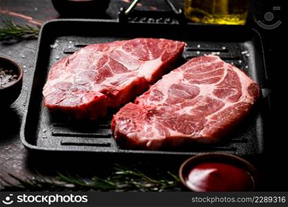 Raw pork steak on a grill pan. Against a dark background. High quality photo. Raw pork steak on a grill pan.