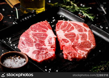 Raw pork steak on a grill pan. Against a dark background. High quality photo. Raw pork steak on a grill pan.