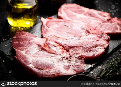 Raw pork steak on a stone board. On a black background. High quality photo. Raw pork steak on a stone board.