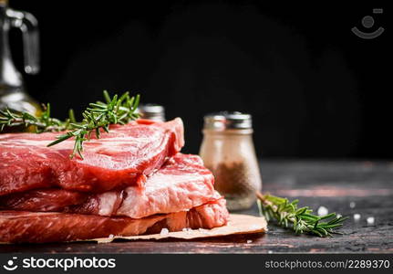 Raw pork steak on paper with rosemary. Against a dark background. High quality photo. Raw pork steak on paper with rosemary.