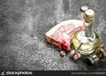 Raw pork steak with olive oil and spices. On rustic background.. Raw pork steak with olive oil and spices.