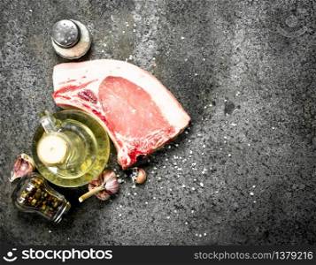 Raw pork steak with olive oil and spices. On rustic background.. Raw pork steak with olive oil and spices.