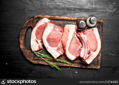 Raw pork steaks on a cutting Board. On the black chalkboard.. Raw pork steaks on a cutting Board.