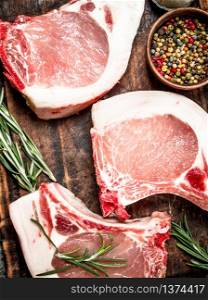 Raw pork steaks with herbs and spices. On rustic background.. Raw pork steaks with herbs and spices.