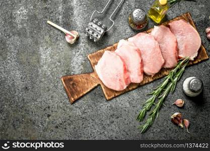 Raw pork steaks with herbs and spices. On rustic background.. Raw pork steaks with herbs and spices.