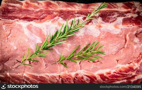 Raw pork with a sprig of rosemary. Macro background. High quality photo. Raw pork with a sprig of rosemary.