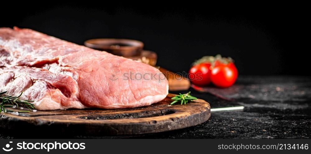 Raw pork with rosemary and tomatoes. On a black background. High quality photo. Raw pork with rosemary and tomatoes.