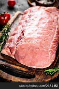 Raw pork with rosemary and tomatoes. On a black background. High quality photo. Raw pork with rosemary and tomatoes.