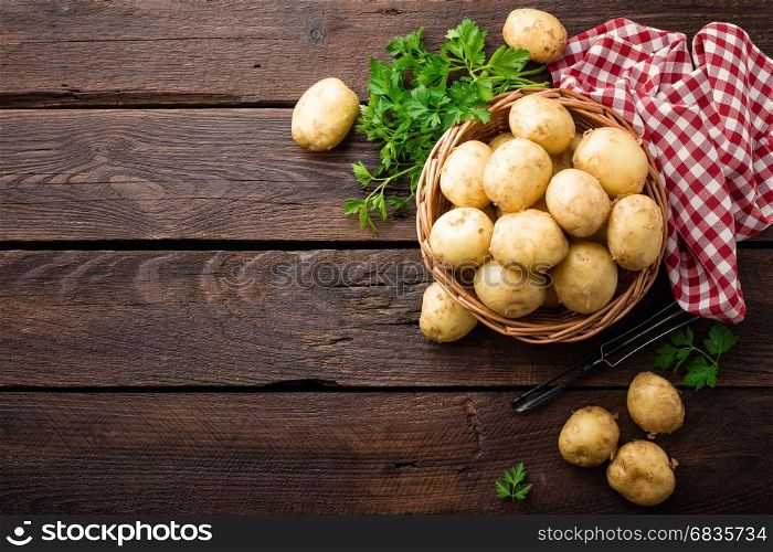 Raw potato in basket on wooden table, top view