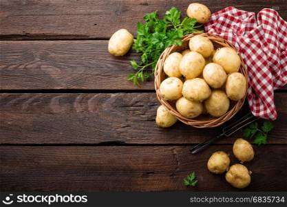 Raw potato in basket on wooden table, top view