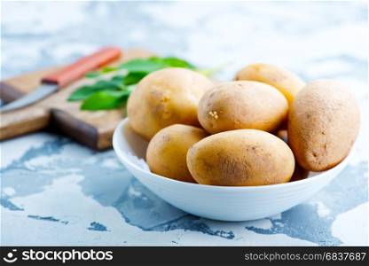 raw potato in bowl and on a table