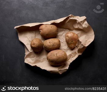 Raw potatoes lie on a brown piece of paper, top view