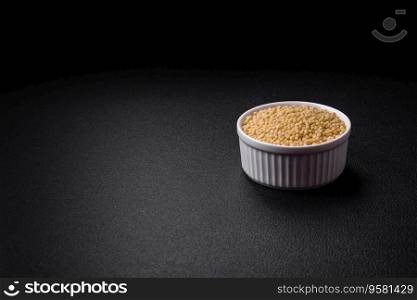 Raw ptitim pasta in a ceramic bowl on a dark concrete background. Israeli food preparation