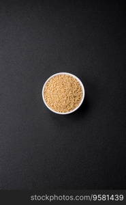 Raw ptitim pasta in a ceramic bowl on a dark concrete background. Israeli food preparation