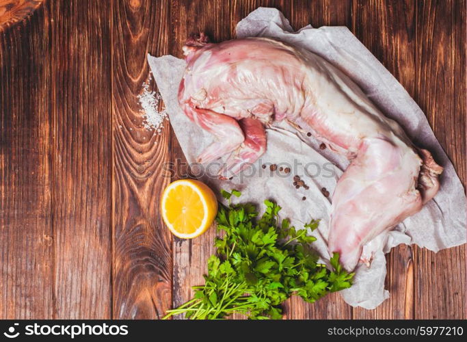 Raw rabbit meat with with lemon, salt and parsley on a wooden background