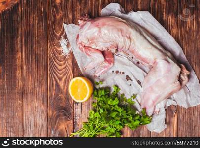 Raw rabbit meat with with lemon, salt and parsley on a wooden background