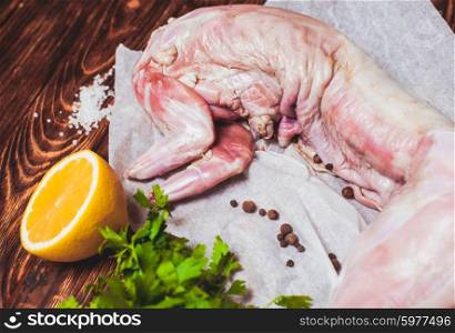 Raw rabbit meat with with lemon, salt and parsley on a wooden background