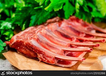 Raw rack of lamb on paper with parsley. On a gray background. High quality photo. Raw rack of lamb on paper with parsley.